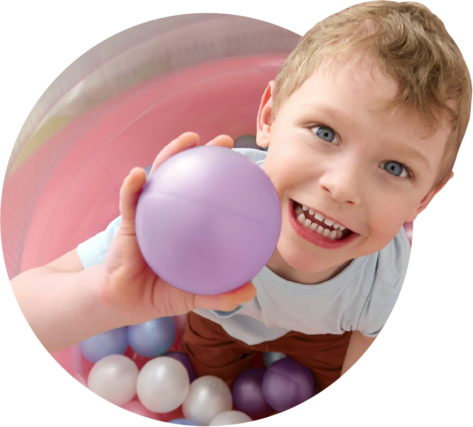 A child holding a purple ball in a ball pit