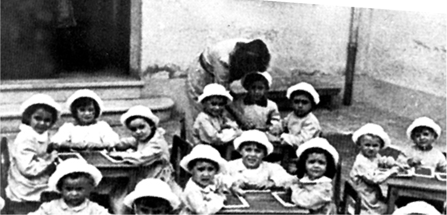 A group of children gathered around classroom tables